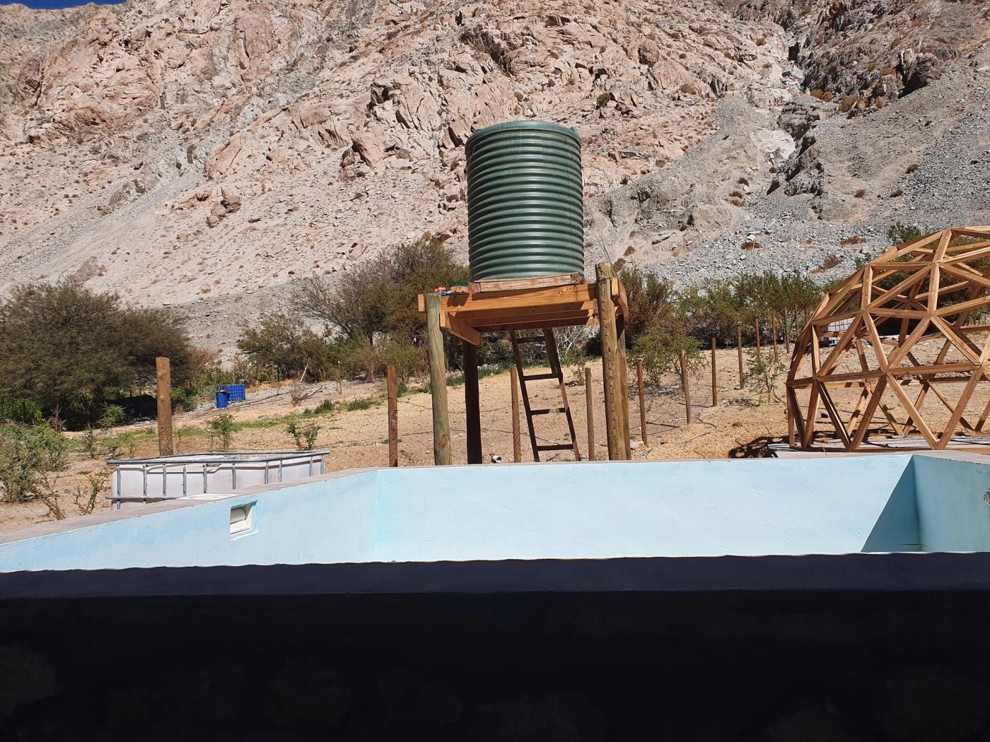 Piscina vacía frente a estanque de agua y ladera rocosa