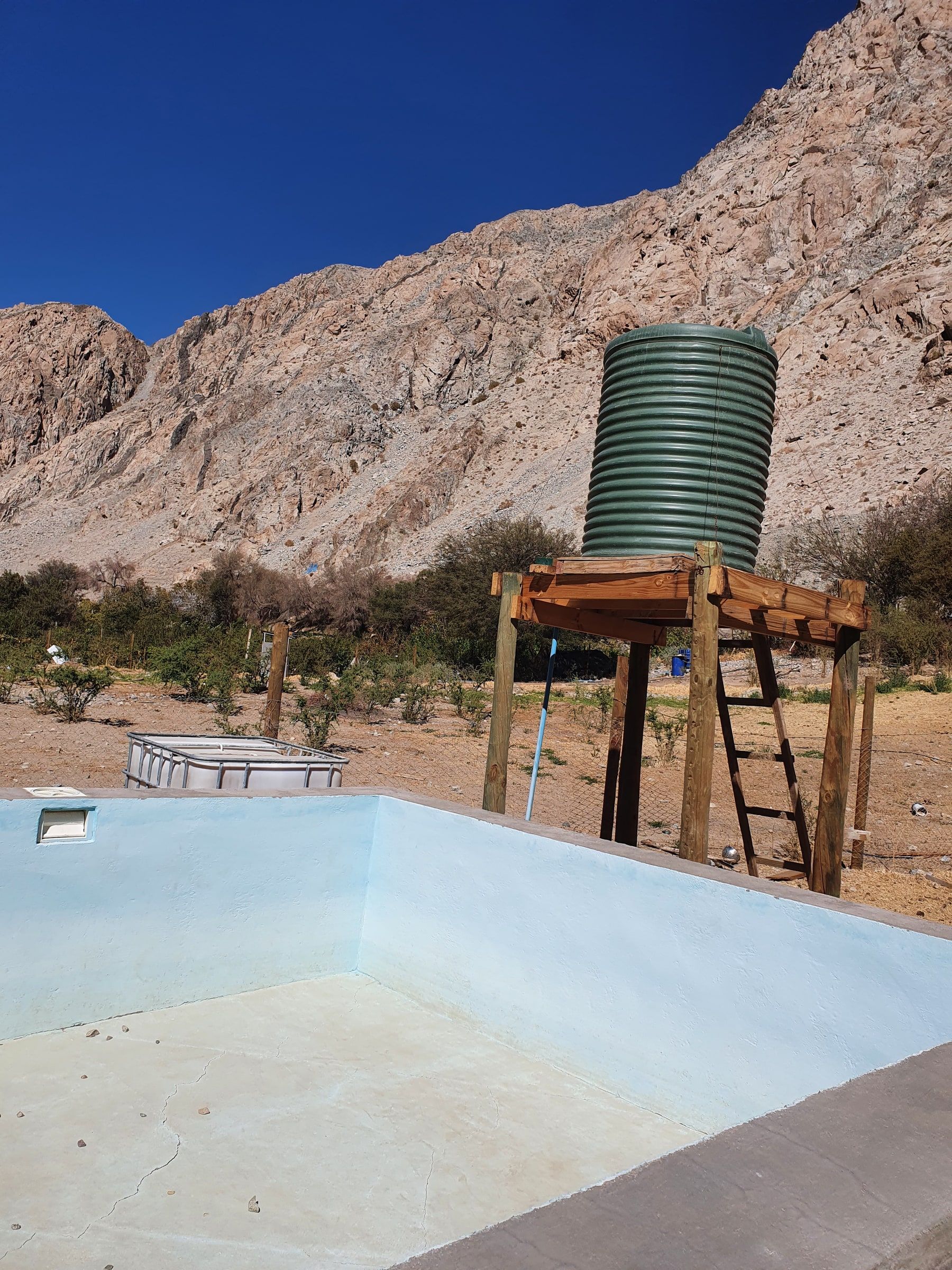 Piscina celeste con estanque elevado y cerro al fondo