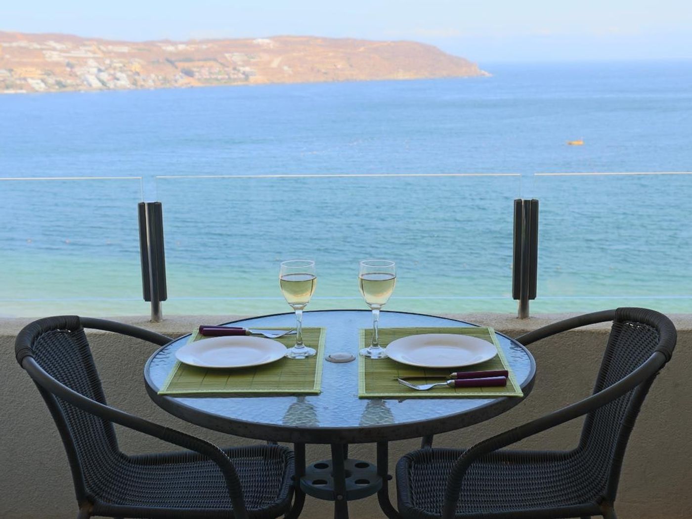Terraza privada con mesa redonda y copas de vino frente a la vista panorámica de la bahía de La Herradura.