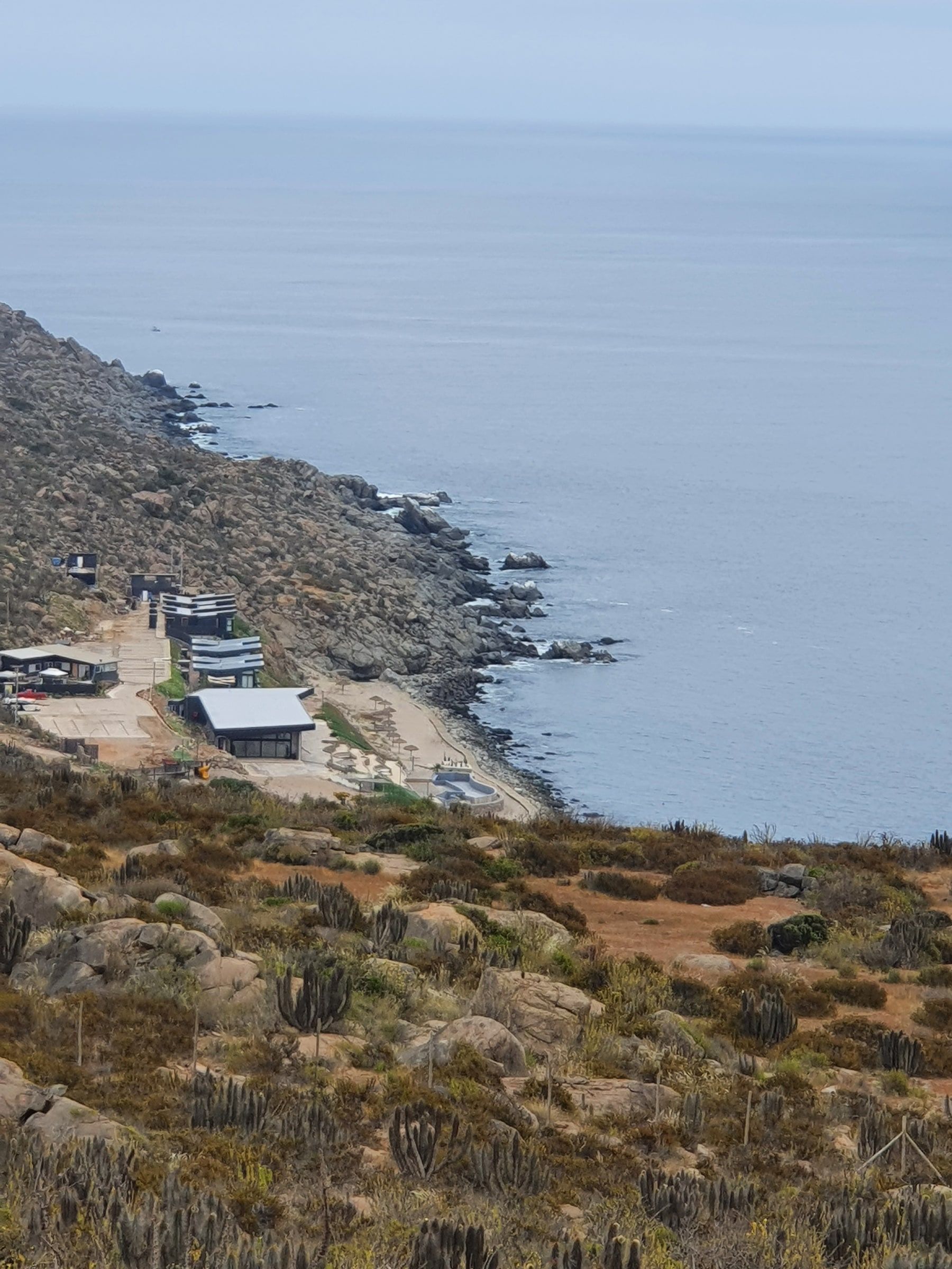 Playa pequeña y punta rocosa con neblina costera