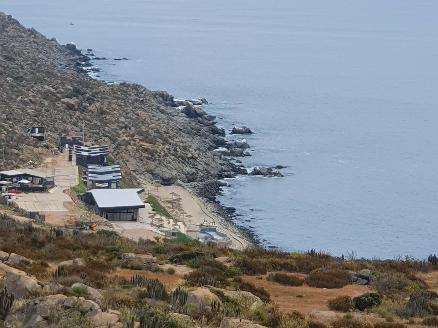 Playa pequeña y punta rocosa con neblina costera