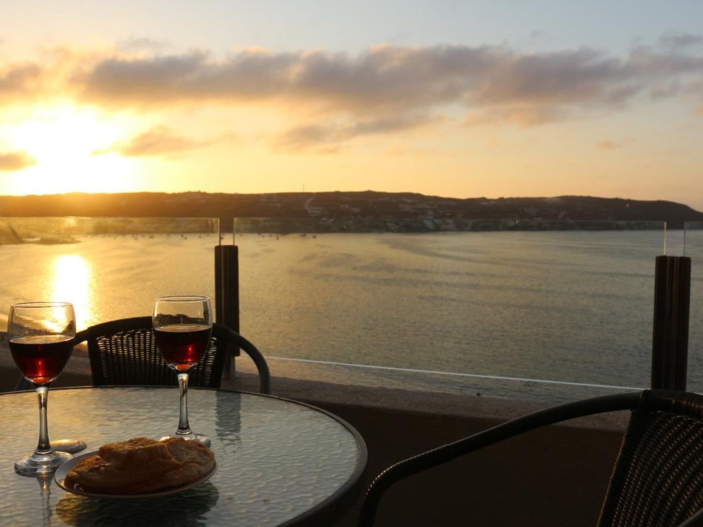 Atardecer dorado sobre la bahía de La Herradura desde la terraza privada del departamento.