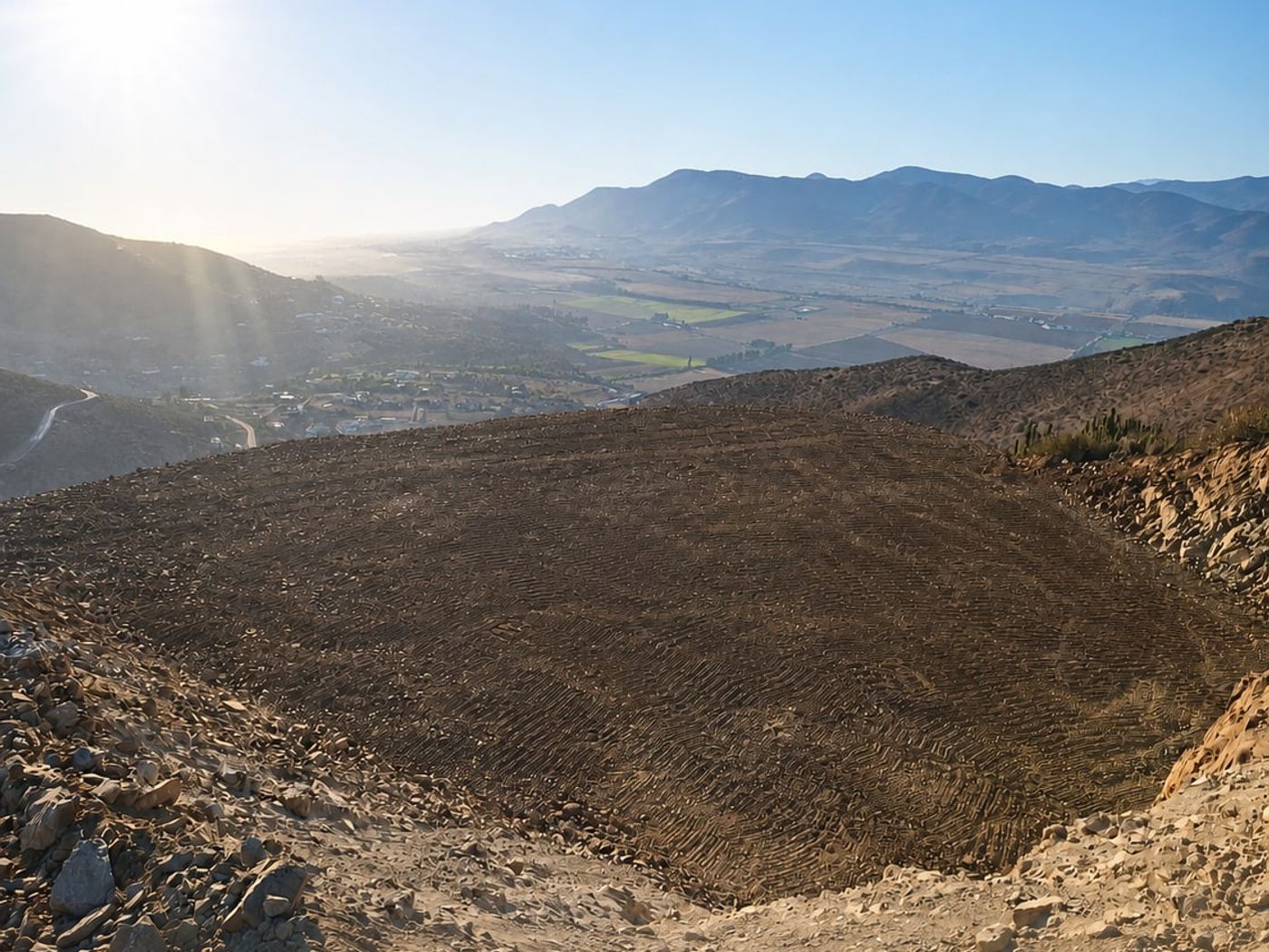 Terraza nivelada en ladera con vista panorámica abierta al Valle de Elqui y sol radiante.