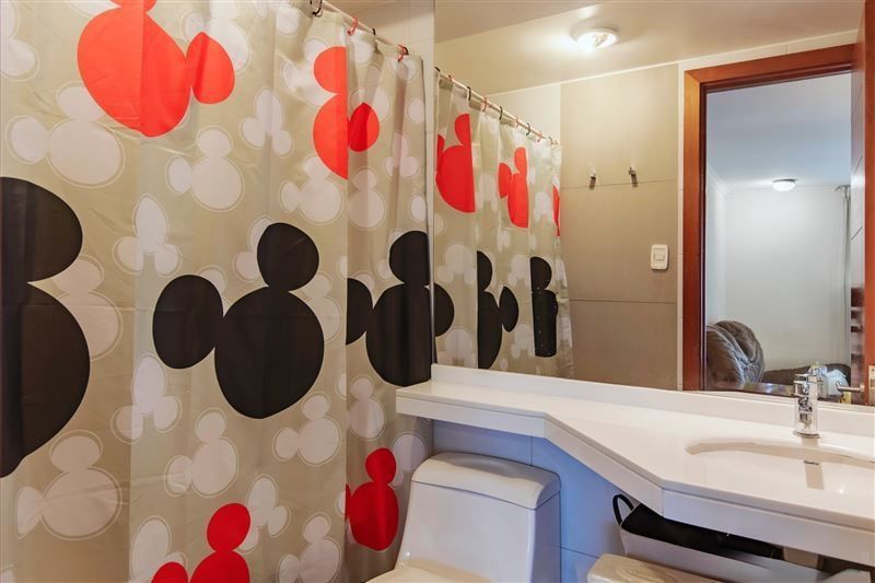 Baño con cortina estampada, lavamanos largo y espejo