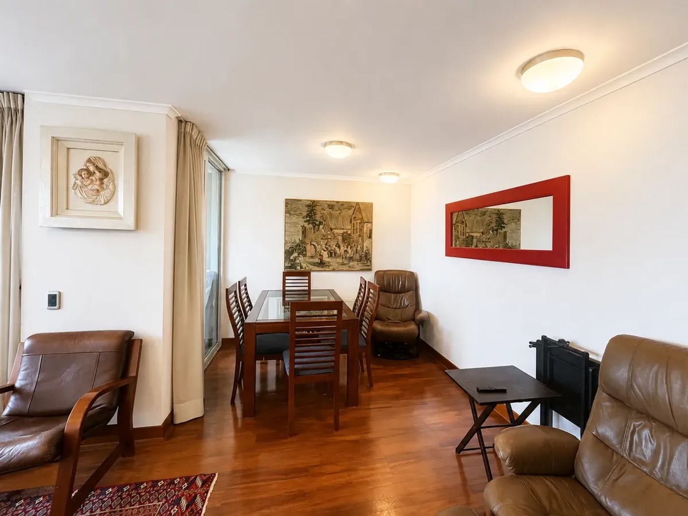 Comedor de madera con seis sillas y cuadros en muro