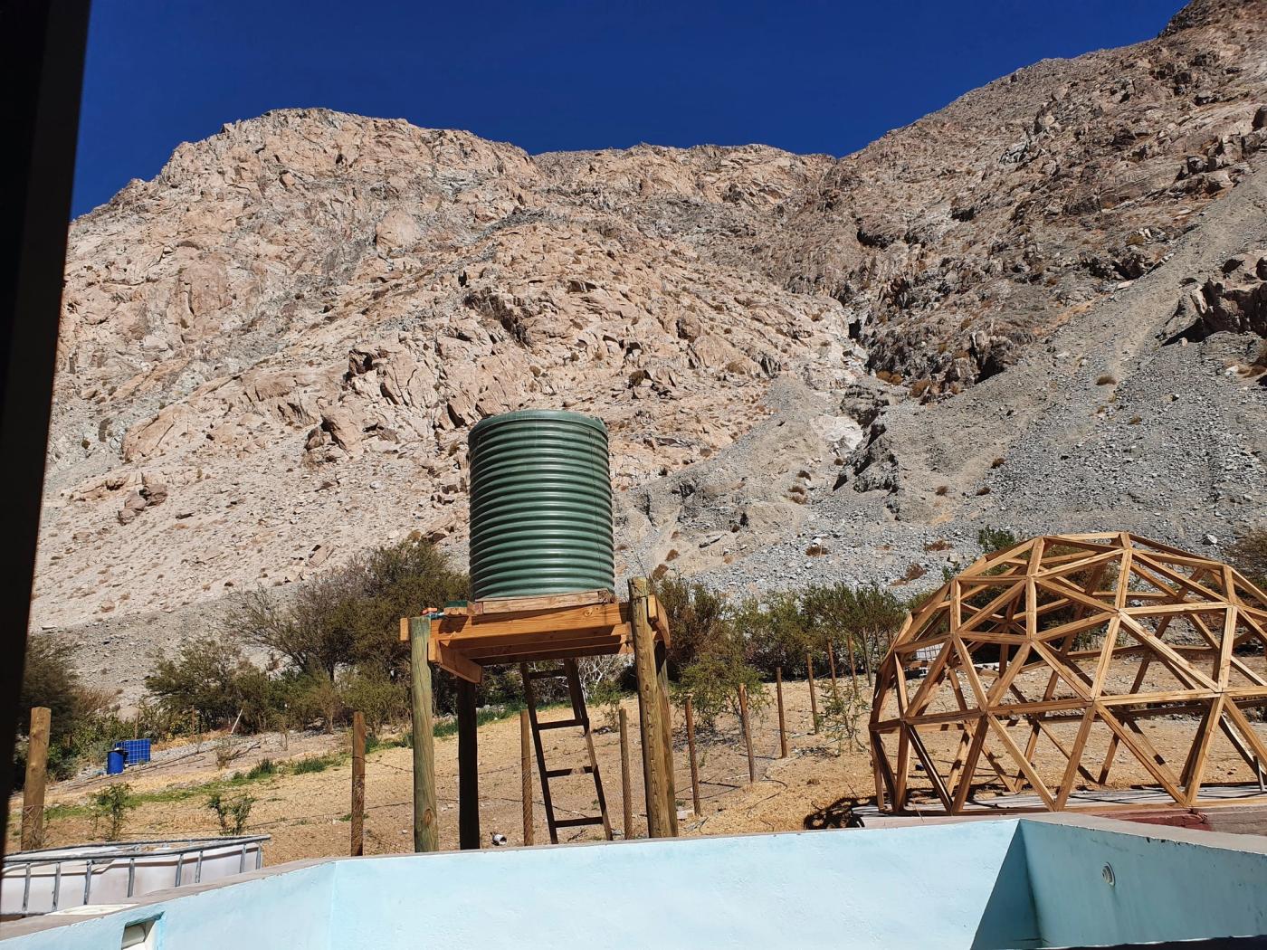 Estanque elevado sobre torre de madera junto a la piscina