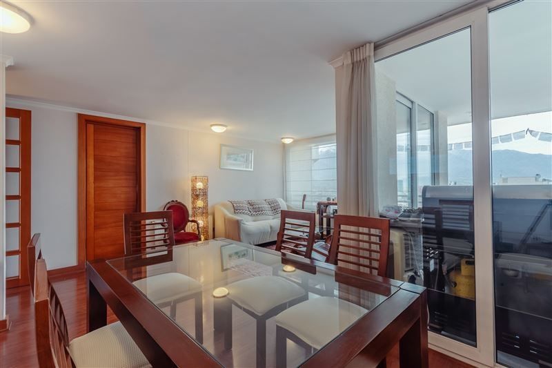 Comedor de vidrio en primer plano y living al fondo