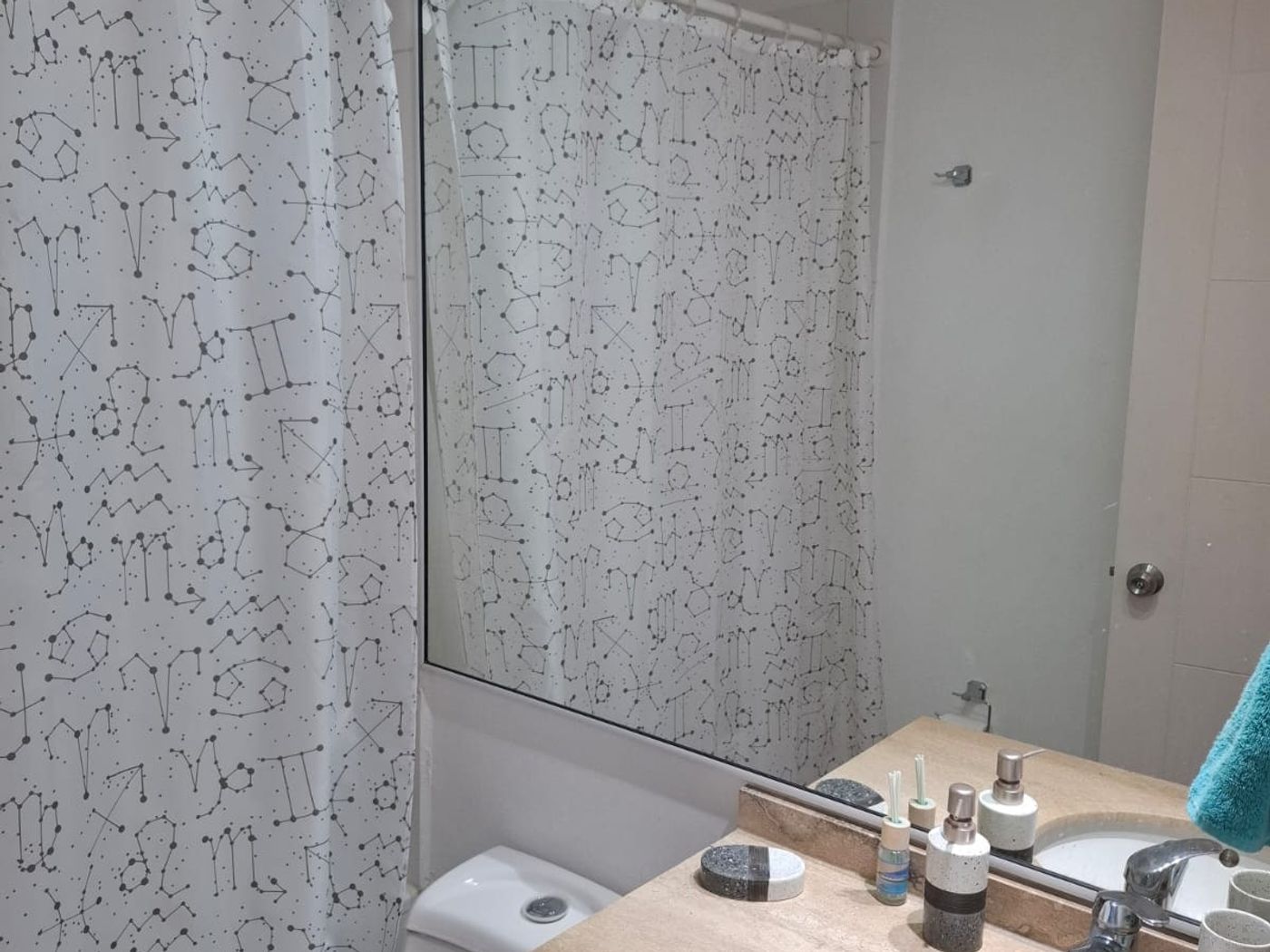 Baño principal completo con vanitorio empotrado, amplio espejo mural e inodoro.