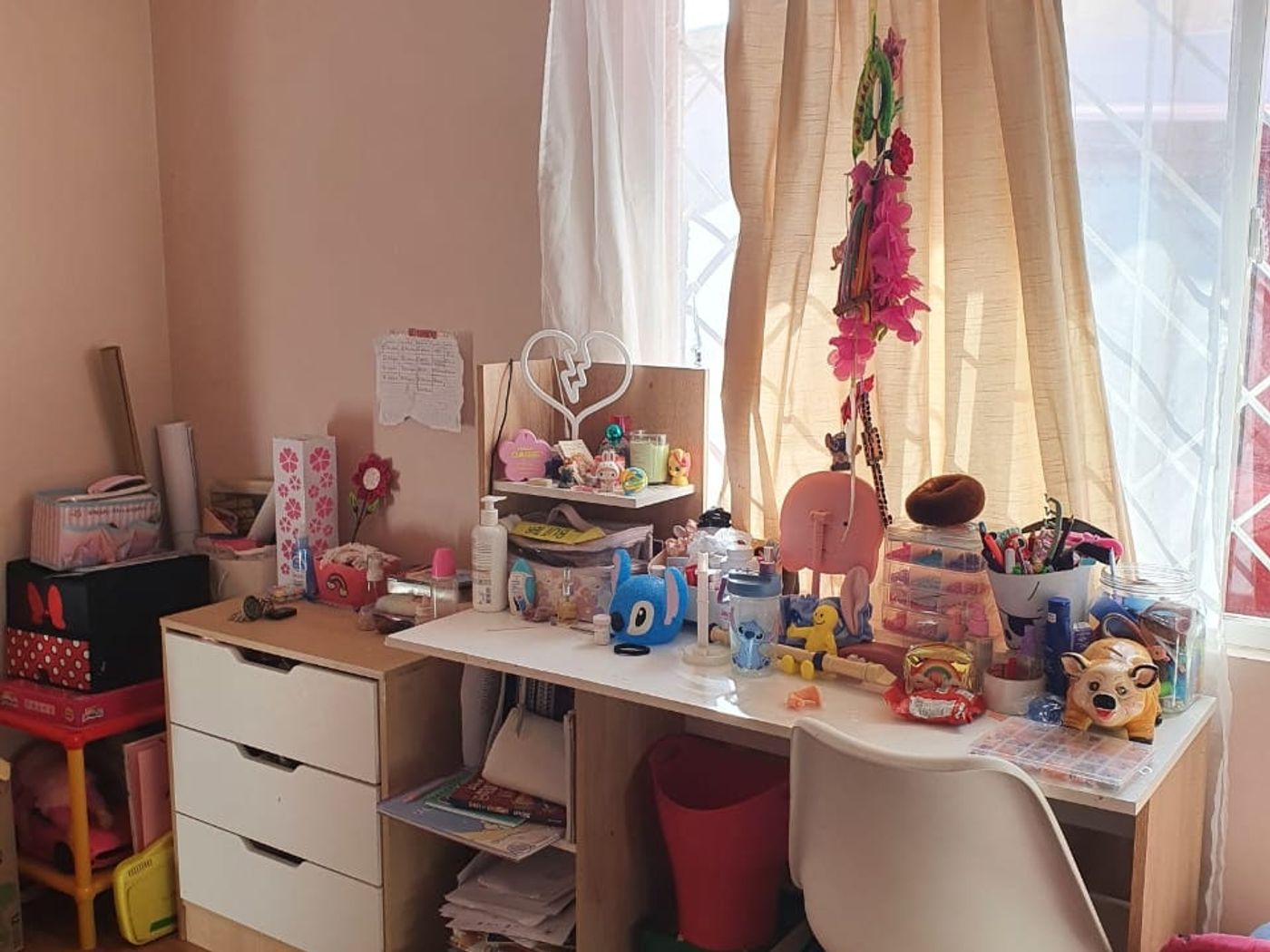 Dormitorio infantil con escritorio, repisas y alfombra, con la superficie cubierta de útiles y juguetes.
