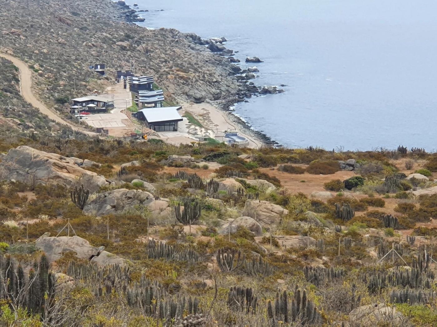 Caleta con restaurantes, playa y roqueríos bajo el terreno