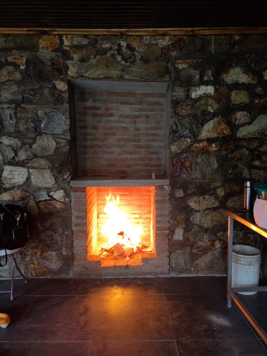 Chimenea de ladrillo encendida en muro de piedra
