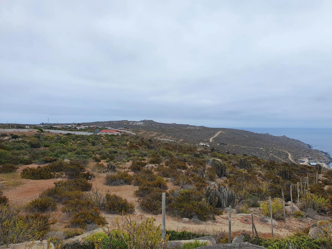 Vista amplia del terreno con caserío y litoral a la derecha