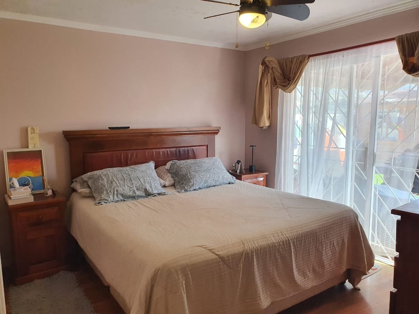 Dormitorio principal completo con cama matrimonial, veladores de madera y cuadro decorativo en la pared.