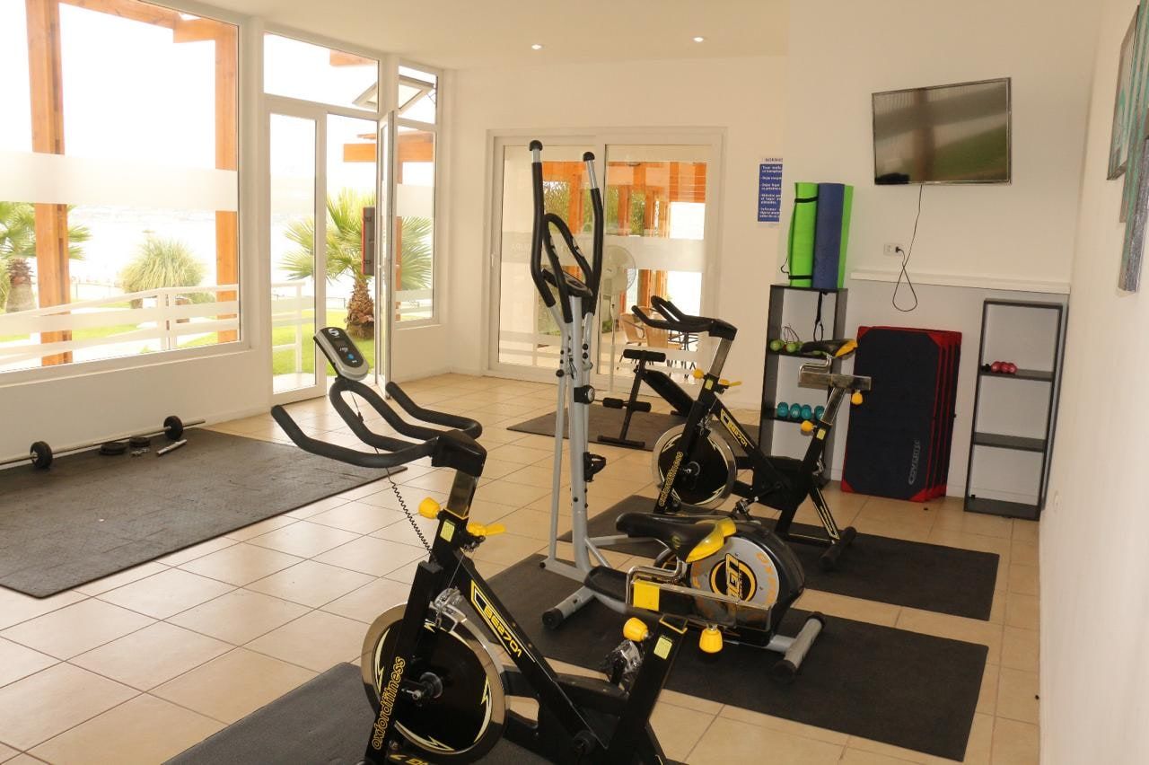 Gimnasio equipado del condominio con máquinas de ejercicio cardiovascular y pesas.