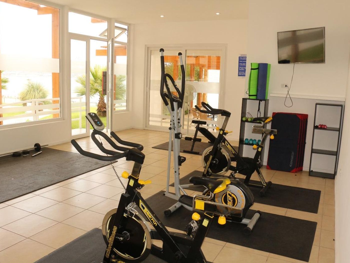 Gimnasio equipado del condominio con máquinas de ejercicio cardiovascular y pesas.