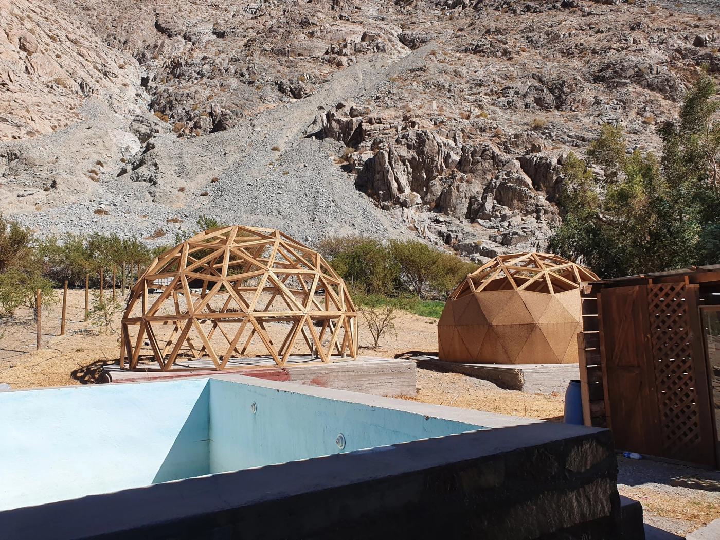 Piscina vacía con domos de madera y cerro detrás