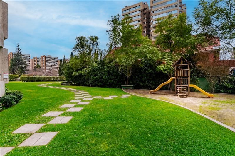 Jardín común con pasto, senderos y juegos infantiles