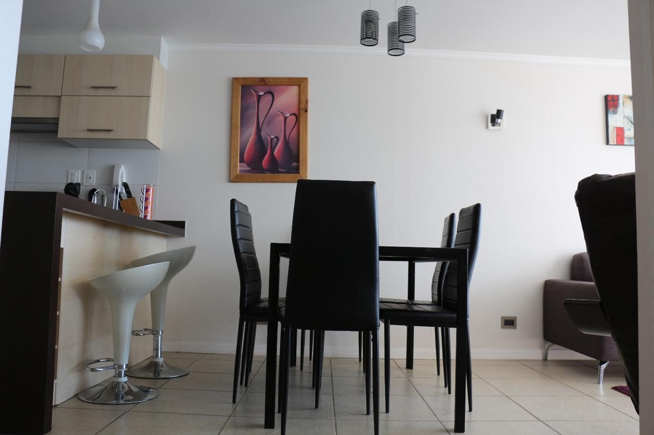 Comedor con mesa contemporánea de cuatro sillas y cuadro decorativo en muro.