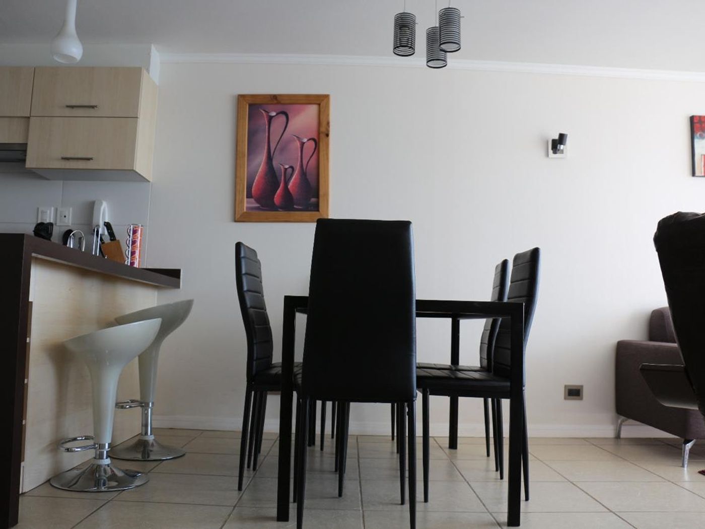 Comedor con mesa contemporánea de cuatro sillas y cuadro decorativo en muro.