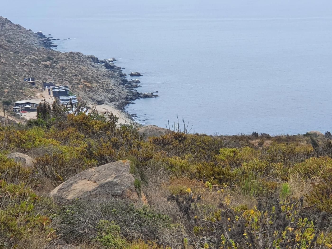 Caleta con casas, playita y roqueríos vistos desde la altura