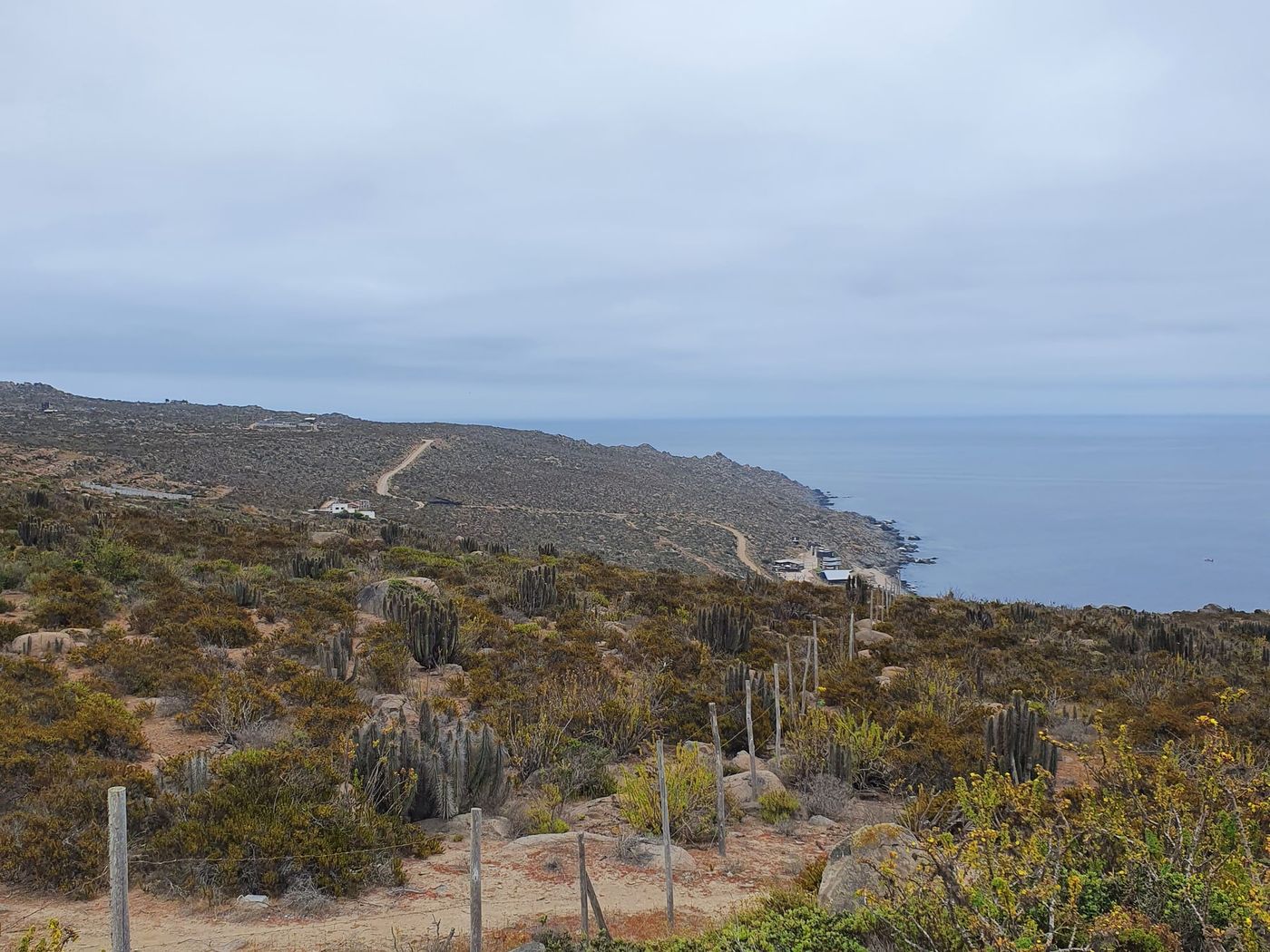 Terreno cercado en pendiente bajando hacia caleta y mar