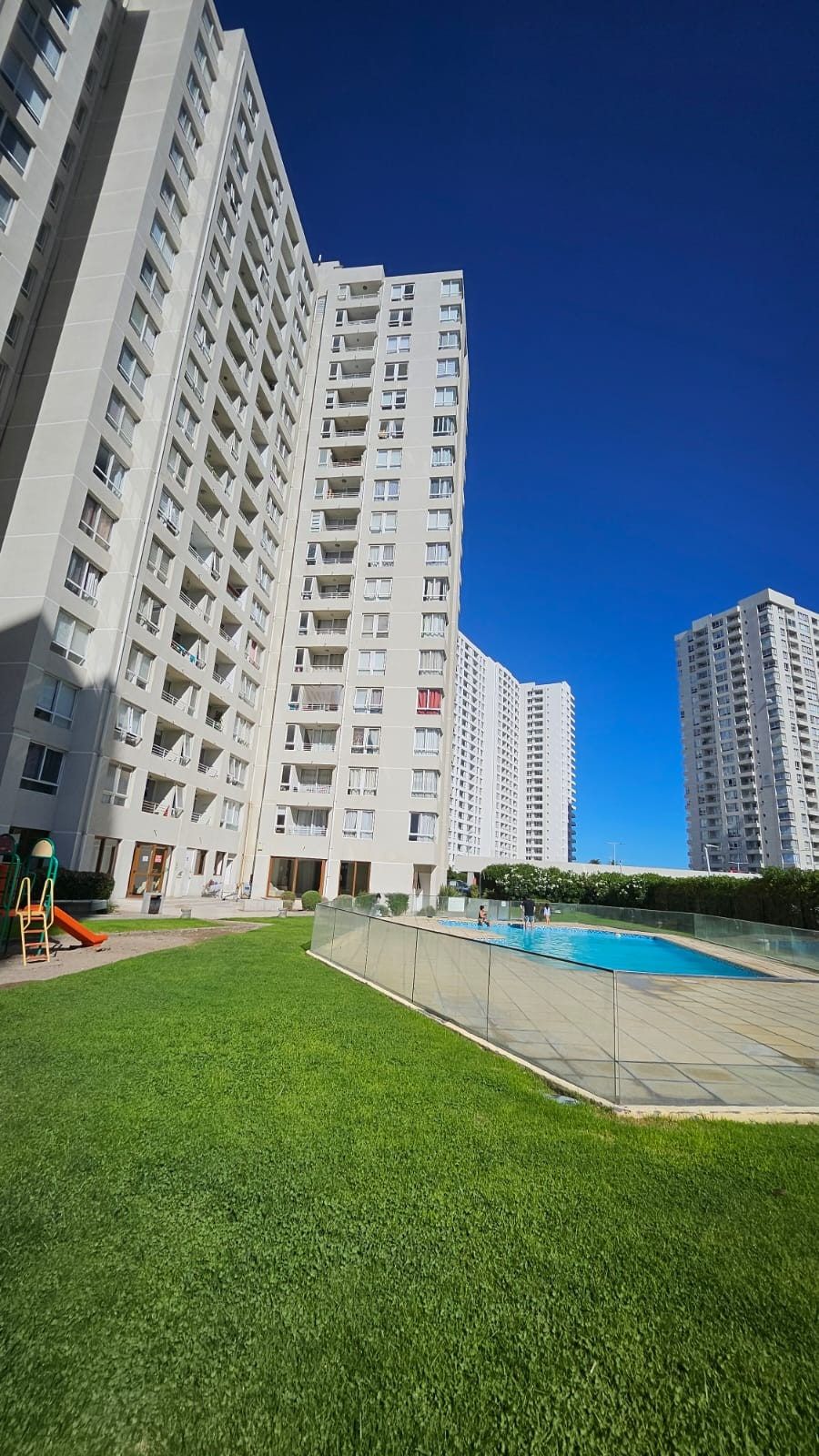 Piscina y áreas verdes entre las torres del condominio