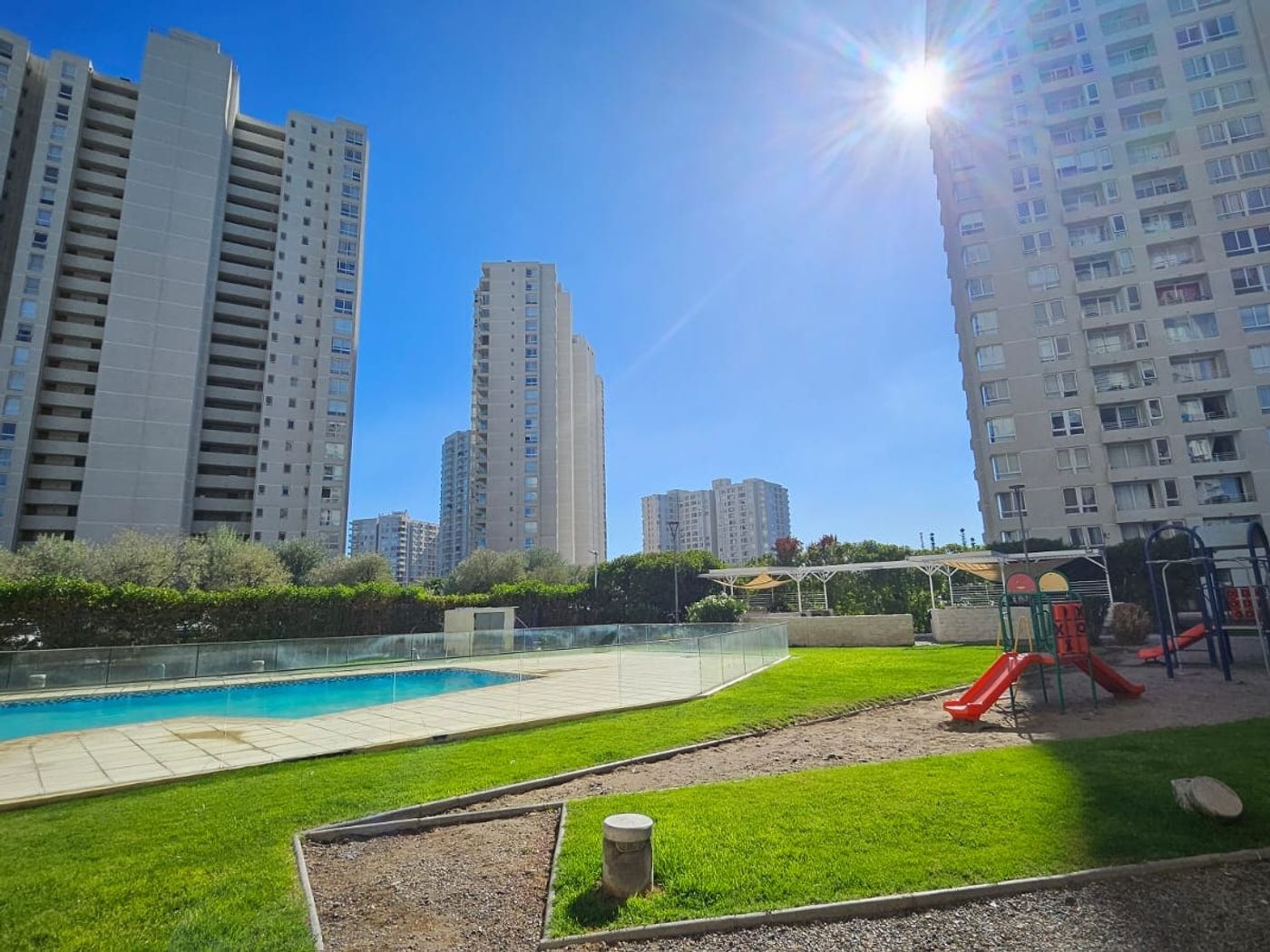 Piscina y jardín del condominio con las torres al fondo