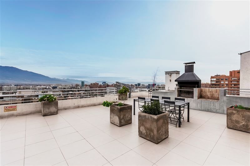 Terraza común en azotea con quincho, mesa y vista a la cordillera
