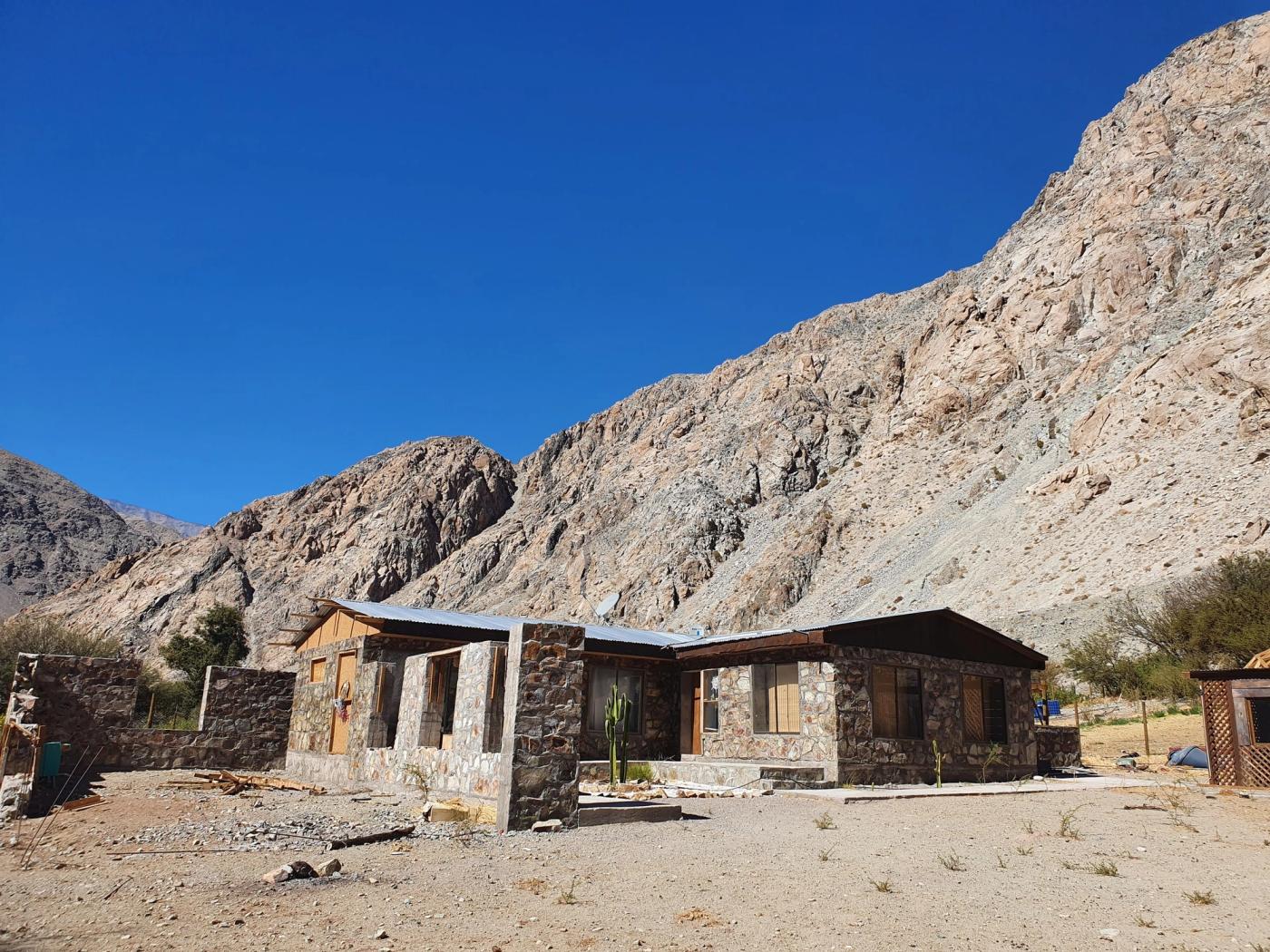 Casa de piedra al pie del cerro con escombros al frente