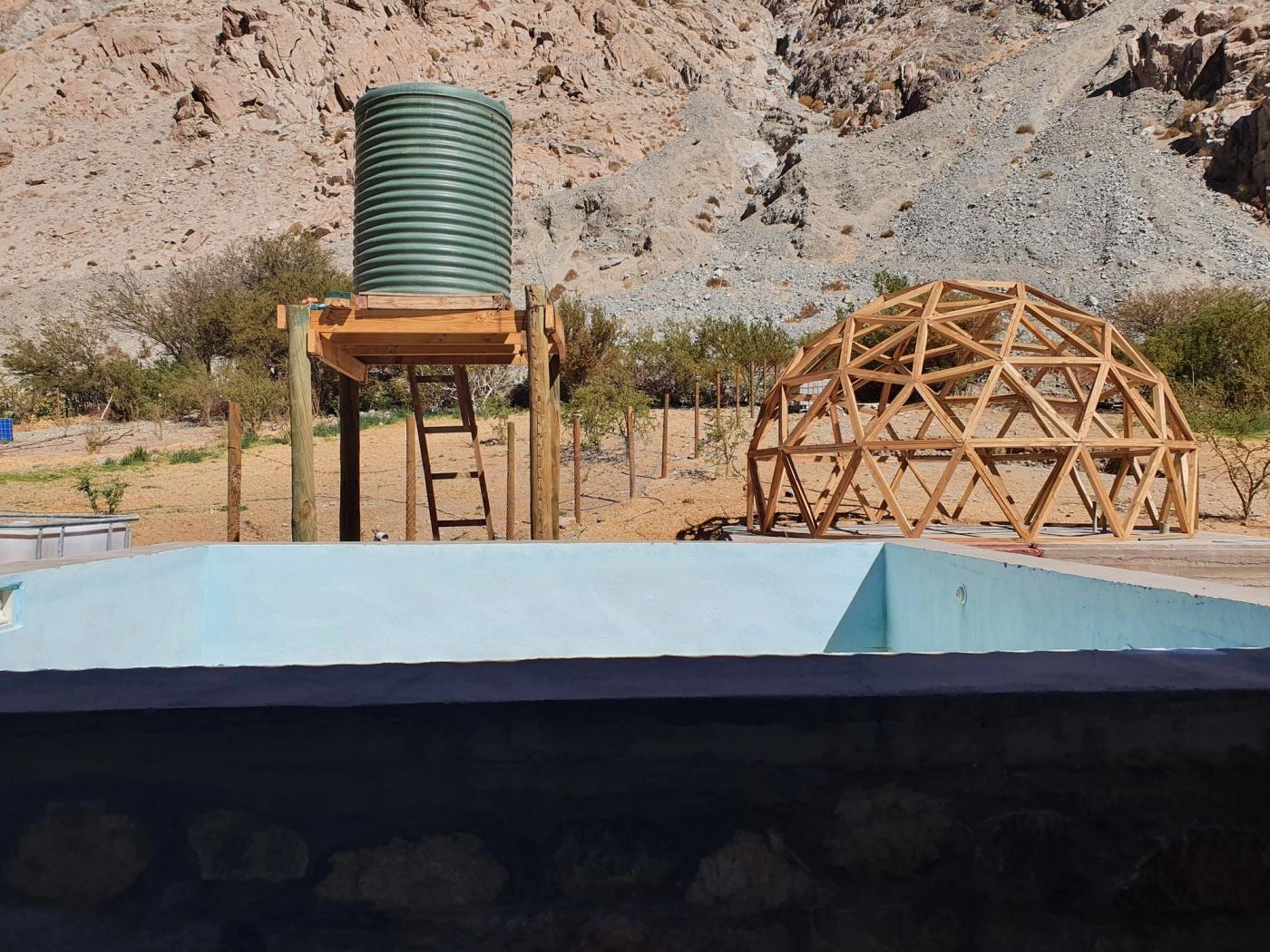 Piscina pintada celeste, estanque elevado y domo de madera