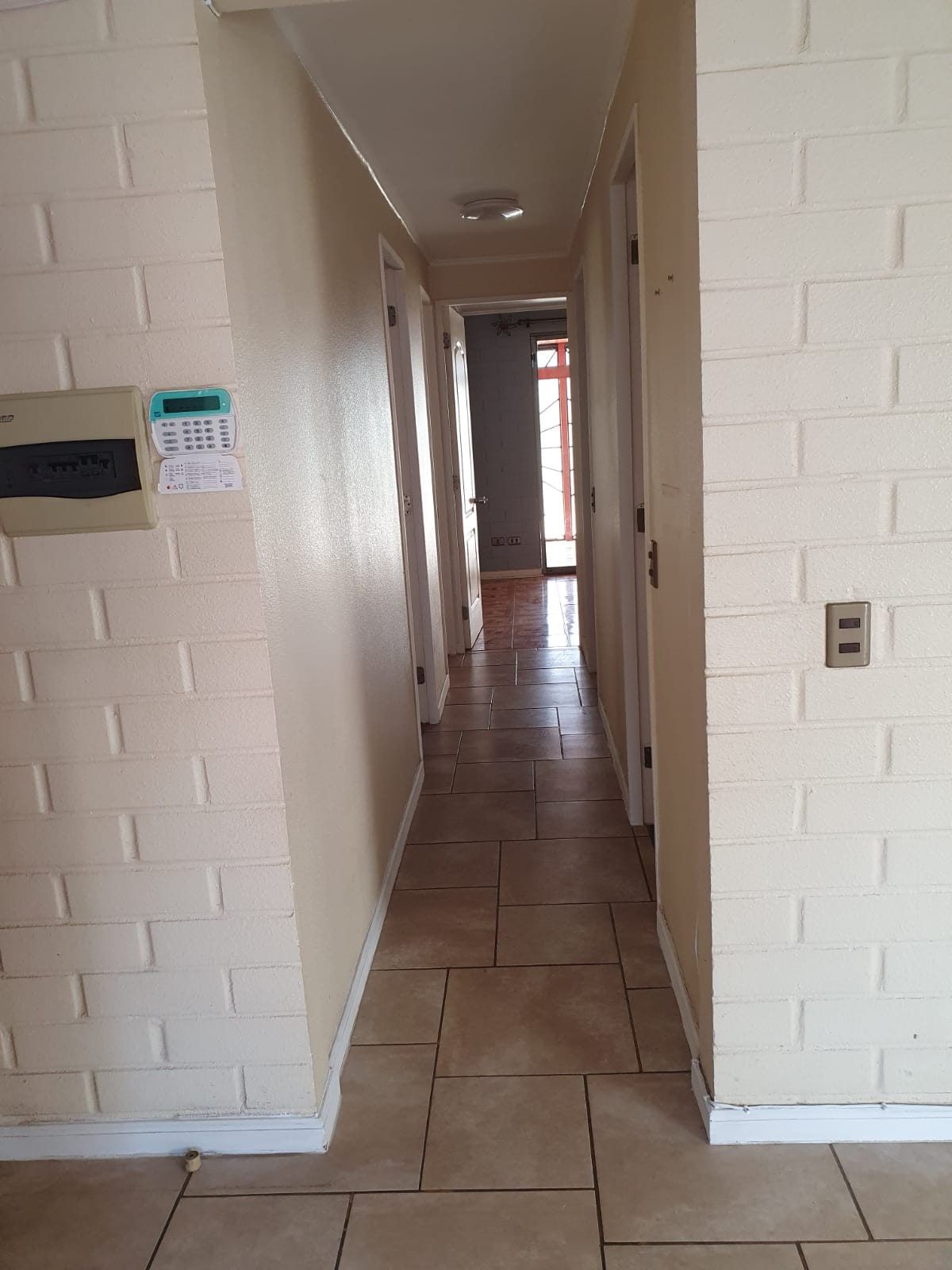 Pasillo interior de distribución con muros de ladrillo a la vista pintados de blanco.
