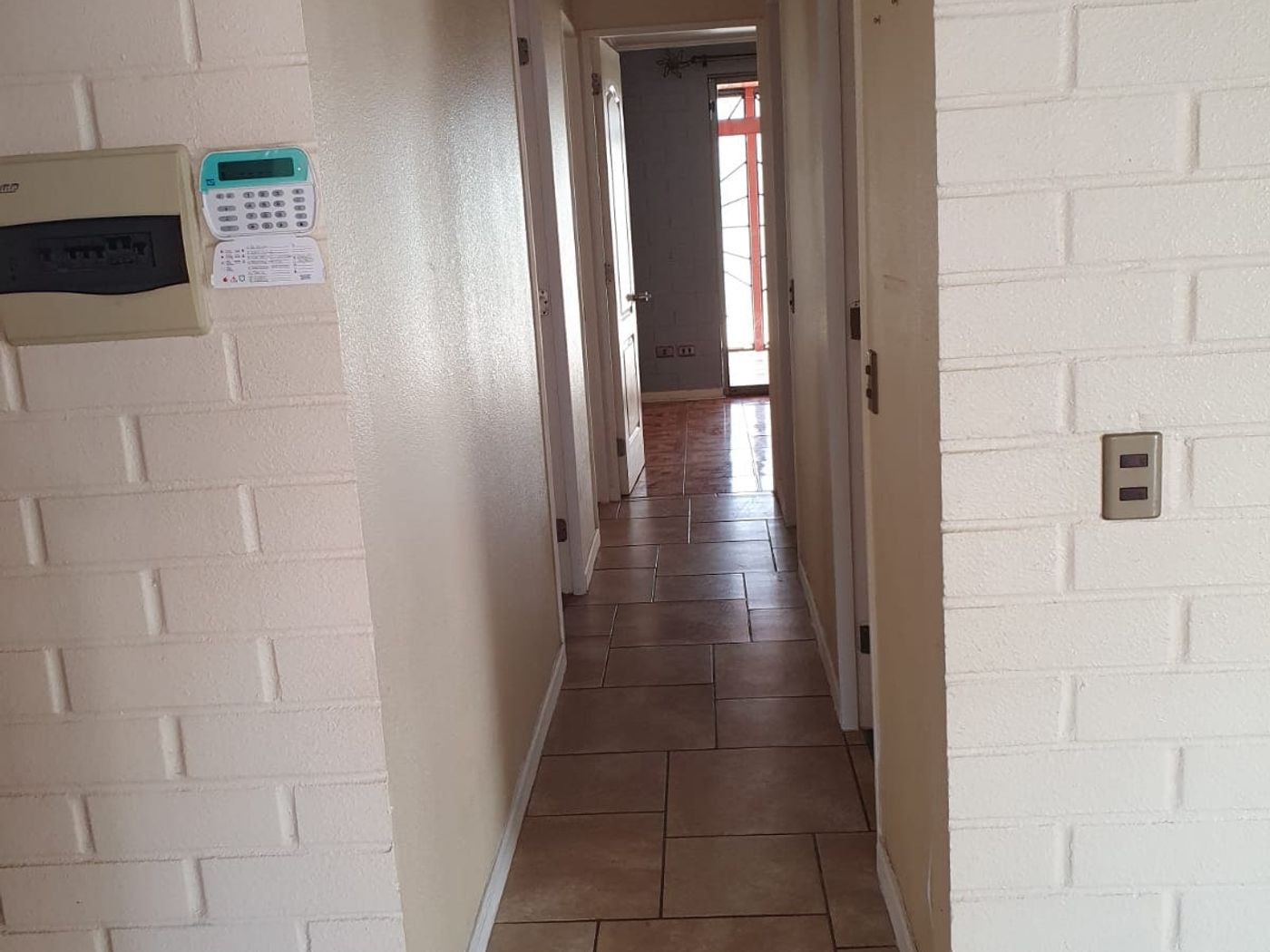 Pasillo interior de distribución con muros de ladrillo a la vista pintados de blanco.