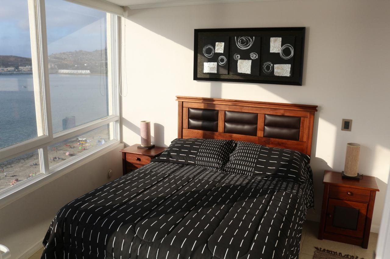 Dormitorio principal con cama matrimonial y amplio ventanal con vista despejada a la bahía.