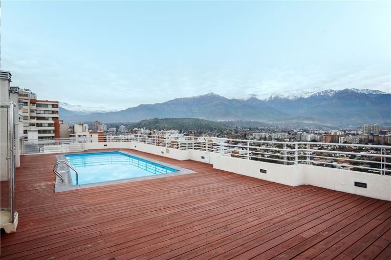 Piscina en azotea con deck de madera y cordillera nevada
