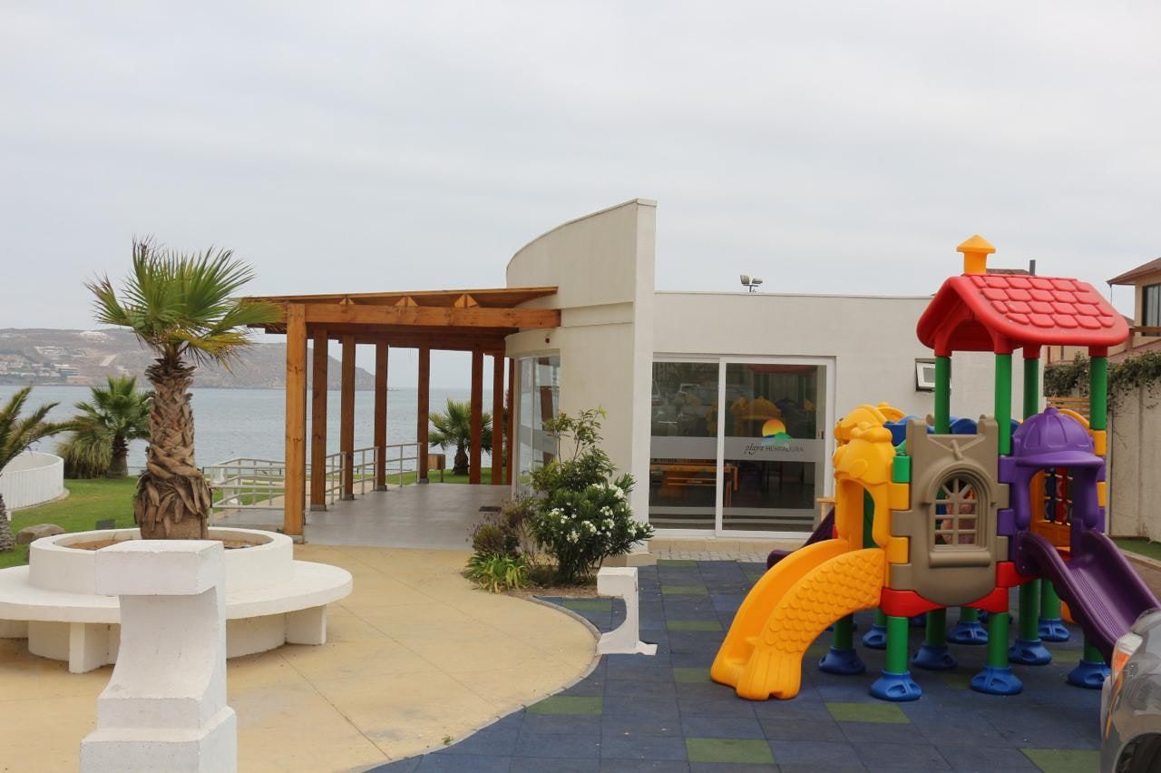 Juegos infantiles modulares en área verde del condominio con vista al mar y la bahía.