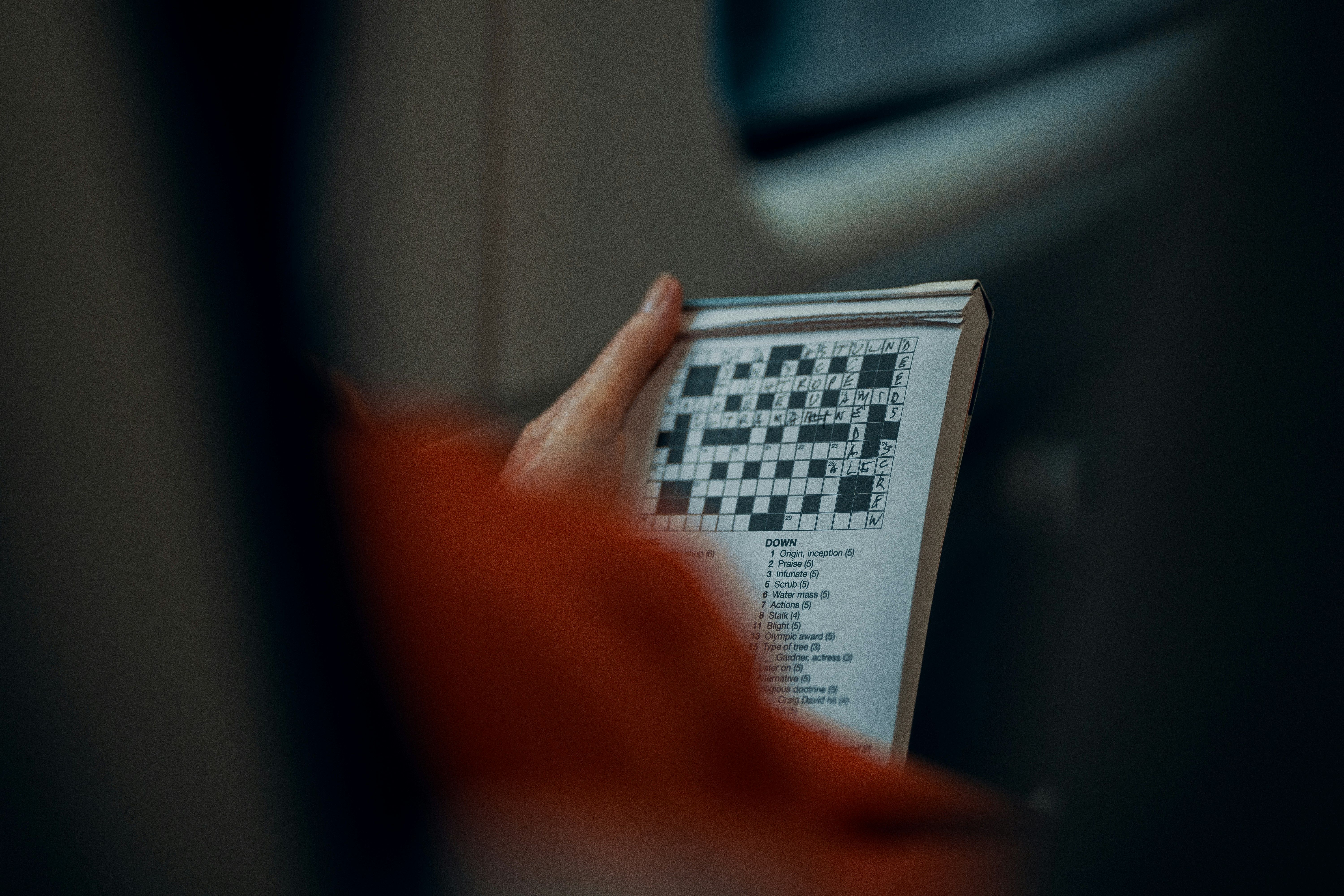 Person holding crossword puzzle paper - beginner guide to Strands
