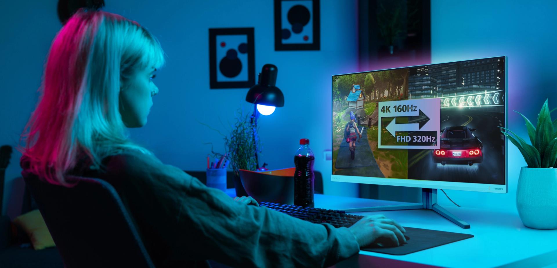 Personne jouant à un bureau avec un moniteur Evnia affichant les options Dual Mode (4K 160 Hz et FHD 320 Hz).