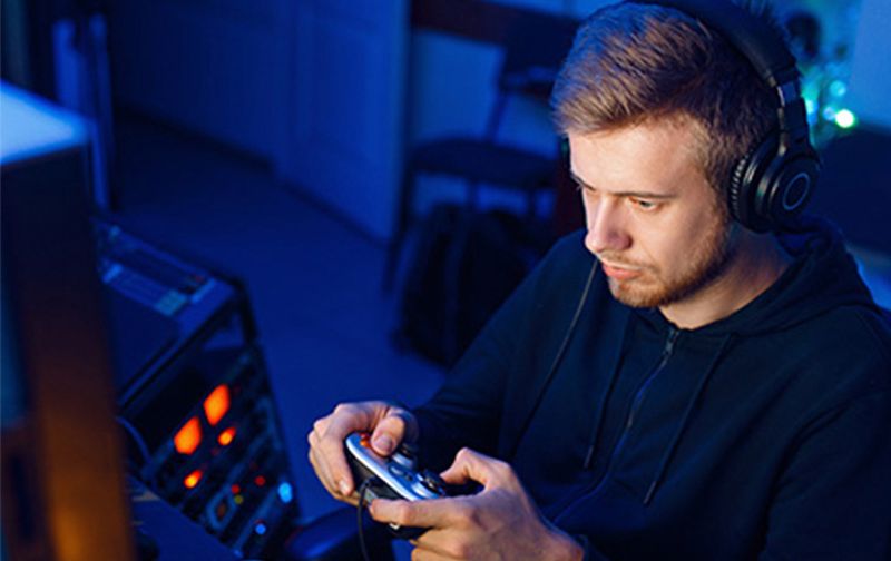 Joueur console utilisant une manette sur un moniteur Evnia, mettant en avant des performances UHD 120 Hz avec une réactivité élevée et un faible input lag.