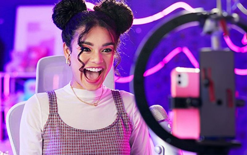 Créateur de contenu enregistrant une vidéo à son bureau avec un ring light, mettant en avant la clarté et la précision 4K pour un travail créatif sur un moniteur Evnia.