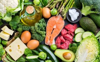A selection of real, low carbohydrate foods, including salmon, beef, cheese, eggs, and leafy green vegetables.