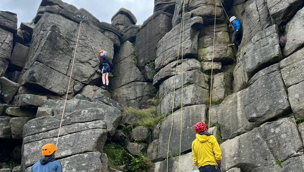 Children rock climbing outdoors in the Peak District