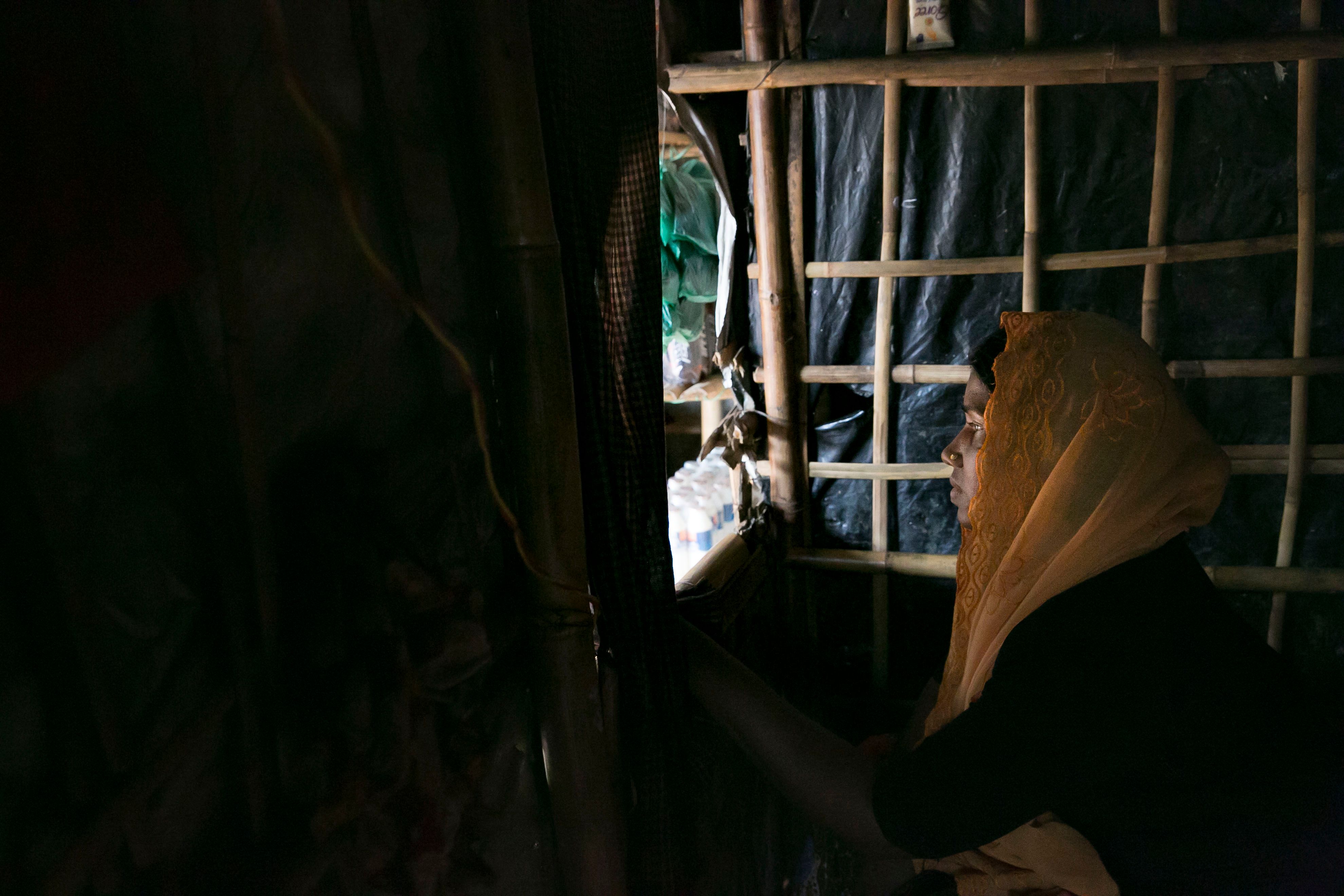 image of Rohingya woman with yellow headscarf looking out a window