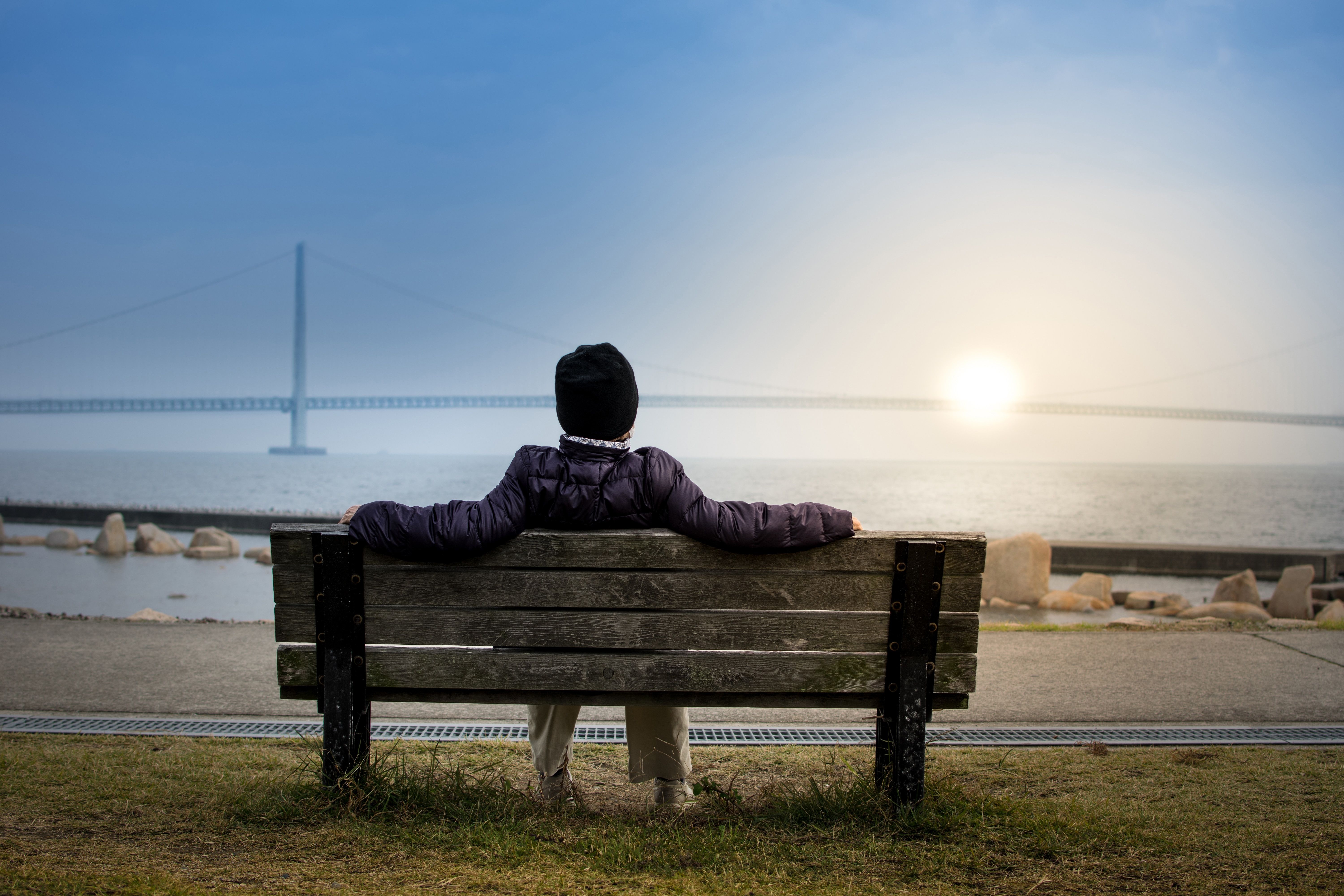 Picture of a person on a bench, resting and looking at the sea 