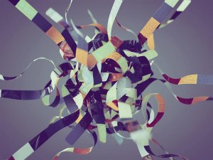 A tangled ball of multi-colored strips on a grey background.