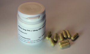 A photo of CBD pills next to a medicine bottle on a white background.