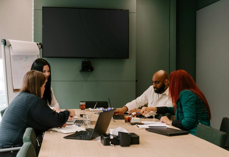 A team collaborates with their laptops in a conference room