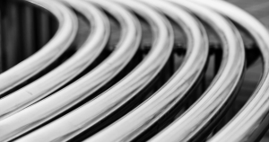 A black-and-white photo of series of silver tubes curving to the left.