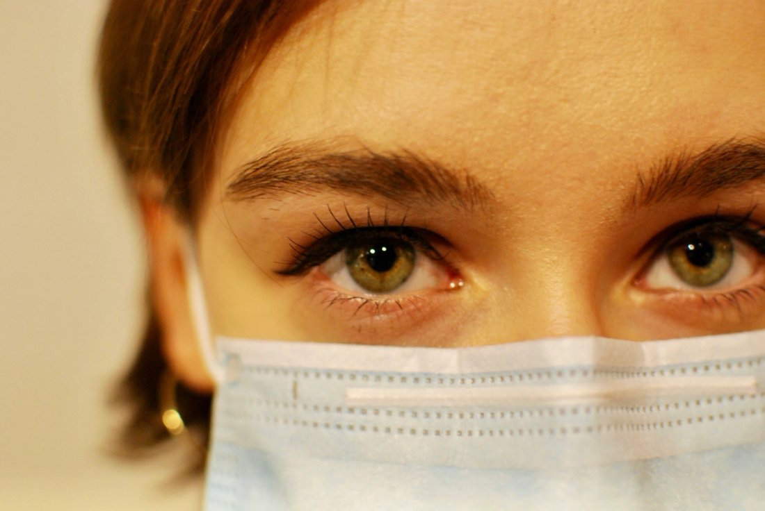 A closeup of a female in a healthcare mask.