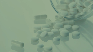 A green-tinted image of a glass jar of pills spilled on a surface