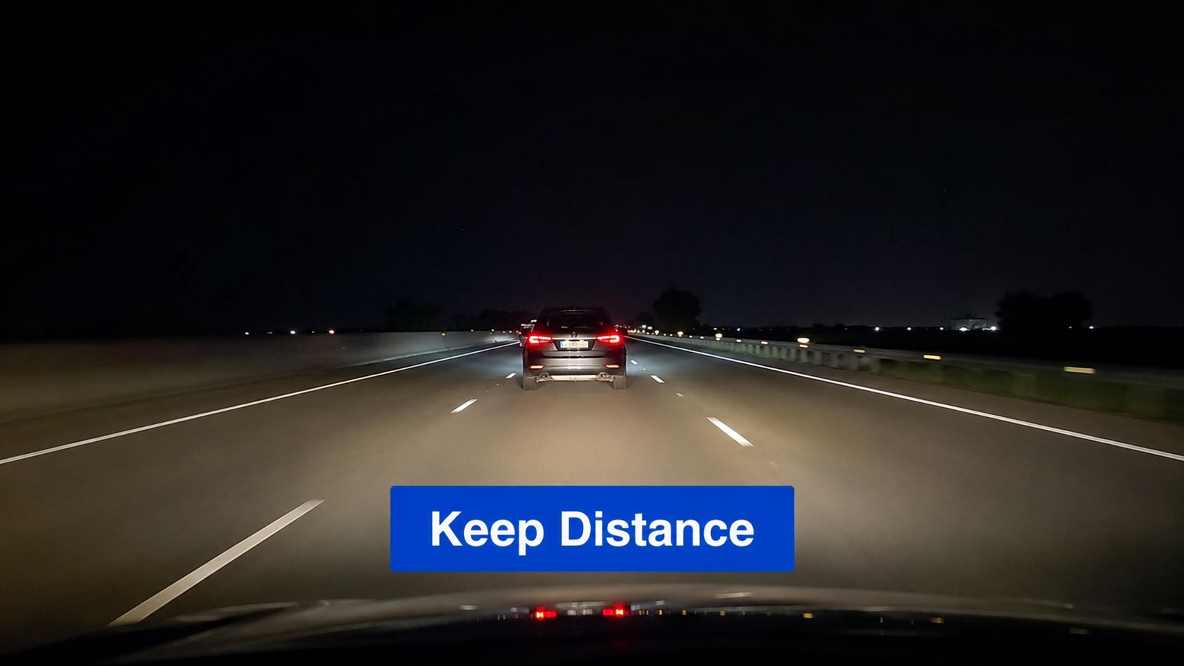 A view from inside a car driving on a highway at night behind another vehicle.